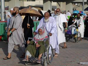 A Muslim worshipper seated in a wheelchair is pushed as she and her escort arrive in Mina to throw pebbles as part of the symbolic al-A'qabah. (AFP)