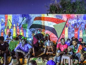 Sudanese protesters sit in front of a recently painted mural during a demonstration near the army headquarters in the capital Khartoum. (AFP)