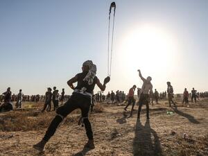 A Palestinian protester uses a slingshot to hurl stones during clashes with Israeli forces near the fence along the border with Israel in the eastern Gaza Strip on August 16, 2019.  (MAHMUD HAMS / AFP)