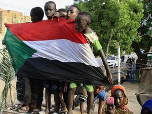 Young Sudanese boys carry a national flag as they celebrate in Bahri, the capital Khartoum's northern district (AFP)
