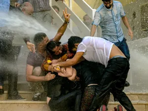 Demonstrators protect each other as they are hit by water cannon during a protest against the replacement of Kurdish mayors with state officials in three cities, in Diyarbakir, in eastern Turkey (AFP)