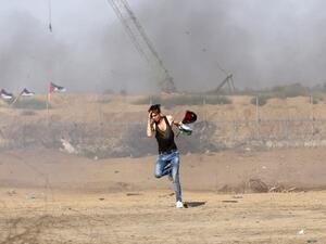A Palestinian man runs for cover during clashes between Palestinian protesters and Israeli forces across the barbed-wire fence. (AFP/ File Photo)
