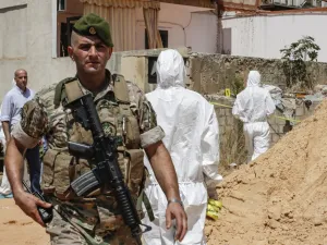 A Lebanese army soldier walks past military intelligence forensic investigators inspecting the scene where two drones came down in the vicinity of a media centre of the Shiite Hezbollah movement  (AFP)