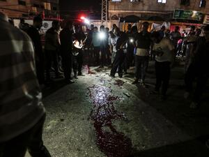 Palestinians look at blood stains on the ground after an unknown explosion near a police checkpoint in Gaza City on August 27, (AFP/ File Photo)