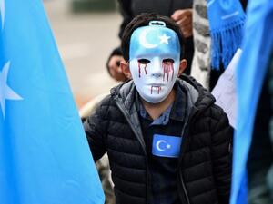 Boy wears mask with tears of blood during recent protest of ethnic Uighurs in Brussels asking EU to pressure China to close 're-education centres' (AFP/file photo)