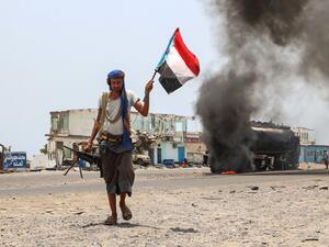 A fighter of the UAE-trained Security Belt Force, dominated by members of the Southern Transitional Council (STC) which seeks independence for south Yemen, walks with a separatist flag past an oil tanker set ablaze in Aden. (AFP/ File Photo)