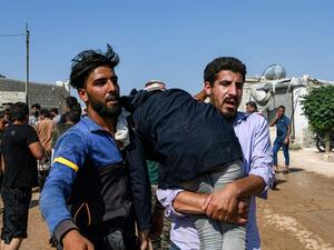 Men carry away a child amidst clashes between displaced Syrians and the Turkish gendarmerie following a demonstration (AFP)