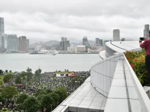 A man takes a photo as protesters gather in Tamar Park to call for a city-wide general strike as they rally against a controversial extradition bill (AFP)