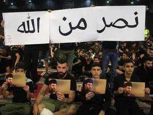 Supporters of the Lebanese Shiite Hezbollah movement hold pictures of the leader Hasan Nasrallah as they watch his speech, transmitted on a large screen in the Lebanese capital Beirut's southern suburbs, on September 2, 2019. (AFP/ File Photo)