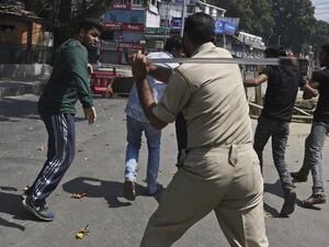 An Indian policeman clashes with Indian Kashmiri Shiite during a strict curfew in Lal Chowk area of Srinagar (AFP)
