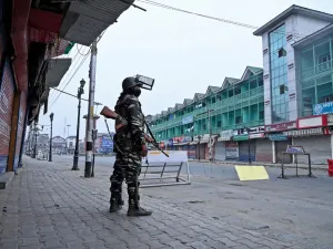 A security personnel stands guard to block a road near closed shops while strict restrictions are imposed during a lockdown in Srinagar on September 28, 2019. (Tauseef MUSTAFA / AFP)