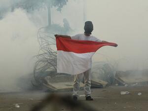 A protester carries the national flag through teargas smoke during a demonstration in Jakarta on September 30, 2019. (AFP/ File Photo)