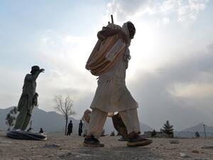 An Afghan labourer carries pipes and equipment on Nadir Khan hill overlooking Kabul on October 1, 2019. (Sajjad HUSSAIN / AFP)