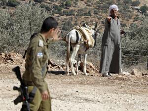 A Palestinian farmer reacts as an Israeli soldier walks past him during a demonstration against the closure of agricultural roads leading to the olive fields in the village of Kafr Thulth, east of Qalqilya in the occupied West Bank, on October 4, 2019. (Jaafar ASHTIYEH / AFP)