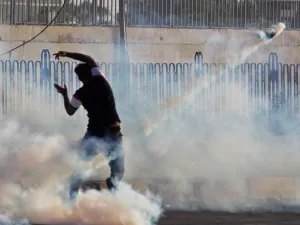 An Iraqi demonstrator gestures amidst smoke from burning tyres and tear gas during a demonstration against state corruption, failing public services and unemployment, in the Iraqi capital Baghdad on October 5, 2019. (AFP/ File Photo)