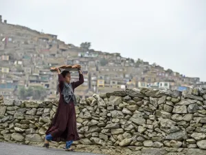 A young girl carries bread on a tray over her head at a hillside overlooking Kabul on October 6, 2019. (WAKIL KOHSAR / AFP)