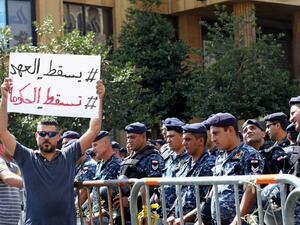 A Lebanese protester holds a placard reading in Arabic "Down with the regime, down with the government" during a demonstration in central Beirut's Martyr Square on October 6, 2019. Lebanese protested in the capital over increasingly difficult living conditions, amid fears of a dollar shortage and possible price hikes. ANWAR AMRO / AFP