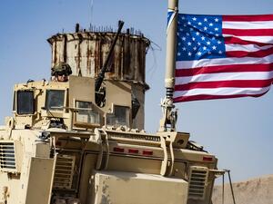 A US soldier sits atop an armoured vehicle during a demonstration by Syrian Kurds against Turkish threats next to a base for the US-led international coalition on the outskirts of Ras al-Ain town in Syria's Hasakeh province near the Turkish border  (AFP)