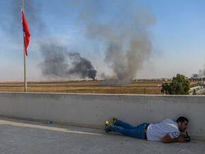 A journalist takes cover in Akcakale near the Turkish border with Syria on October 10, 2019 as a mortar landed nearby, on the second day of Turkey's military operation against Kurdish forces. (AFP)