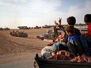 Syrian Arab civilians flash the victory sign as Turkish armoured personnel carriers and US-made M60 taks gather in the village of Qirata on the outskirts of the northern Syrian city of Manbij near the Turkish border, on October 14, 2019. (AFP/ File Photo)