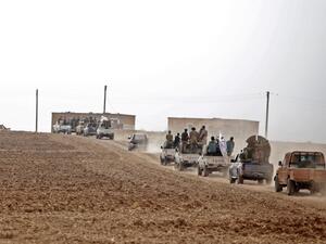 A convoy of pickup trucks transports Turkey-backed Syrian fighters on the road between the Syrian towns of Tal Abyad and Kobane (AFP)