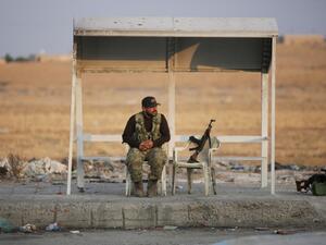 A turkish-backed Syrian fighter sits on the side of the street in the town of Ayn al-Arus, south of the border town of Tal Abyad (AFP)