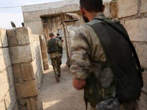 Turkey-backed Syrian fighters leave a house that they are using as a postition in the Syrian border town of Ras al-Ain (AFP)