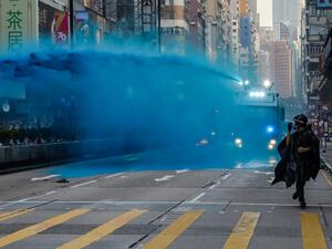 A protester runs from advancing police as they deploy a water cannon on a road in the Tsim Sha Tsui district in Hong Kong on October 20, 2019. Police fired water cannon and tear gas at Hong Kongers who defied authorities with an illegal march on October 20, their numbers swollen by anger over the recent stabbing and beating of two pro-democracy protesters.  DALE DE LA REY / AFP