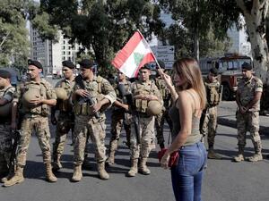 A Lebanese woman waves a national flag in front of soldiers standing guard on a main road in the eastern outskirts of the capital Beirut on October 22, 2019. Lebanese protesters gathered for a sixth consecutive day today, keeping the country on lockdown to demand new leaders despite the government's adoption of an emergency economic rescue plan.  ANWAR AMRO / AFP