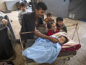 A Displaced Syrian man soothes a baby inside a school turned into a shelter for people displaced by the war, in the northeastern Syrian town of Hasakeh, on October 25, 2019. (AFP/ File Photo)