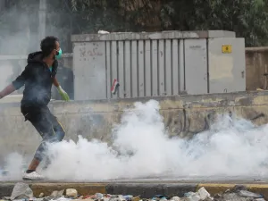 An Iraqi demonstrator runs through a cloud of tear gas during continuing anti-government protests in the centre of Baghdad on October 27, 2019. The Iraqi capital and south have been rocked by a second wave of demonstrations since October 24, with protesters persevering despite tear gas, curfews and violence that has left over 60 dead. (AFP/ File Photo)