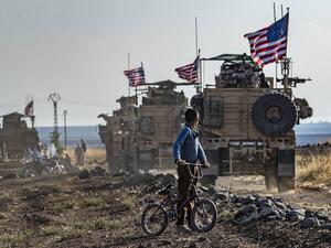 A Syrian boy on his bicycle looks at a convoy of US armoured vehicles patrolling fields near the northeastern town of Qahtaniyah at the border with Turkey, on October 31, 2019. US forces accompanied by Kurdish fighters of the Syrian Democratic Forces (SDF) patrolled part of Syria's border with Turkey, in the first such move since Washington withdrew troops from the area earlier this month, an AFP correspondent reported. Delil SOULEIMAN / AFP