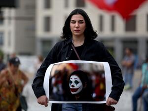 Lebanese protester Cynthia Aboujaoude holds a picture of her face painted as the Joker in downtown Beirut on October 23, 2019 as demonstrations to demand better living conditions and the ouster of a cast of politicians who have monopolised power and influence for decades continue. Patrick BAZ / AFP