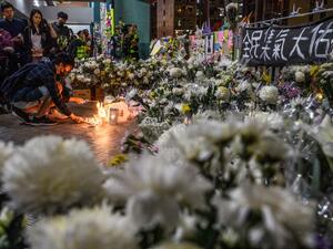 Mourners pay their respects next to flowers and a banner which reads "From all of us - God bless Chow Tsz-Lok" at the site where student Alex Chow, 22, fell during a recent protest in the Tseung Kwan O area on the Kowloon side of Hong Kong on November 8, 2019. (AFP)