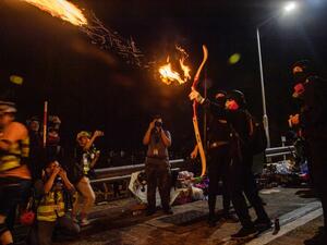 A protester releases a fire arrow with his bow to light a barricade at the Chinese University of Hong Kong (CUHK), in Hong Kong early on November 13, 2019. Hong Kong pro-democracy protesters fought intense battles with riot police on a university campus and paralysed the city's upmarket business district Tuesday, extending one of the most violent stretches of unrest seen in more than five months of political chaos. Anthony WALLACE / AFP