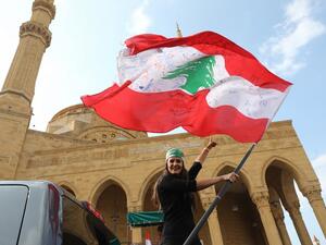 A Lebanese anti-government protester waves the national flag as she prepares to head to the south of Lebanon on a 'revolution' bus from central Beirut on November 16, 2019. ANWAR AMRO / AFP