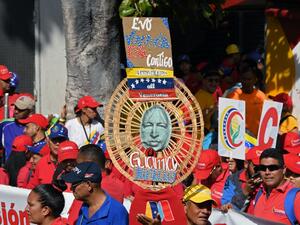 Pro-government supporters hold a sign reading "Evo, Venezuela is with you" and the image of Venezuelan late President Hugo Chavez, during a demo in Caracas, on November 16, 2019. Venezuela's opposition called to protest against President Nicolas Maduro on Saturday, while the government also called on their own supporters to mobilize. (YURI CORTEZ / AFP)