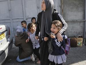 Women attempt to protect school children as they attempt to flee while stuck in clashes surrounding a demonstration demonstration by Israel's controversial separation barrier (AFP)