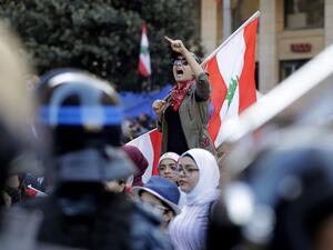 A Lebanese protester holds a national flag as she chants slogans during a demonstration at Riad al-Solh square near the government palace and the parliament headquarters in the capital Beirut's downtown district on November 19, 2019. (AFP/ File Photo)