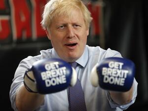 Britain's Prime Minister and leader of the Conservative Party, Boris Johnson wears boxing gloves emblazoned with "Get Brexit Done" as he poses for a photograph at Jimmy Egan's Boxing Academy in Manchester north-west England on November 19, 2019, during a general election campaign trip. Britain will go to the polls on December 12, 2019 to vote in a pre-Christmas general election. Frank Augstein / POOL / AFP
