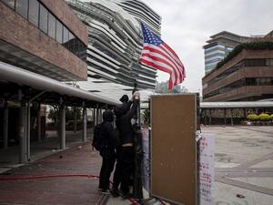 Protesters raise a US flag inside the Hong Kong Polytechnic University in the Hung Hom district of Hong Kong on November 20, 2019. A dwindling number of exhausted pro-democracy protesters barricaded inside the Hong Kong university defied warnings on November 19 to surrender, as a police siege of the campus stretched through a third day and China sent fresh signals that its patience with nearly six months of unrest was running out.
