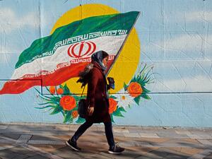 An Iranian woman walks past a mural painting of the Islamic republic's national flag in central Tehran on November 21, 2019. (AFP/ File Photo)