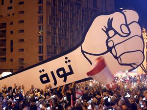 Lebanese demonstrators raise a new giant sign of a fist that bears the Arabic word "revolution" on it, in the Lebanese capital Beirut's Martyr's Square on November 22, 2019, after the sign was burnt overnight by unknown perpetrators. (AFP/ File )