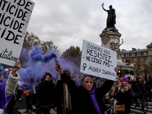 A woman holds a flare and a placard reading "Remember, resist, do not give in" during a protest to condemn violence against women, on November 23, 2019, in Paris. (Alain JOCARD / AFP)