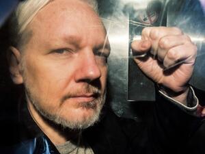 WikiLeaks founder Julian Assange gesturing from the window of a prison van as he is driven into Southwark Crown Court in London, before being sentenced to 50 weeks in prison for breaching his bail conditions in 2012. (AFP/ File Photo)