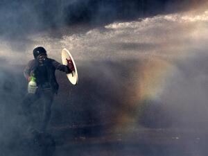 A demonstrator protects himself from the spray of a police water cannon with a makeshift shield during a protest against the government in Santiago on November 26, 2019. (AFP/ File Photo)