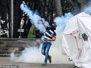 A demonstrator hurls a tear gas canister back to the riot police on the streets of Bogota yesterday. (AFP/ File Photo)