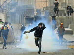 An Iraqi demonstrator runs for cover from teargas fired by Iraqi security forces in Baghdad's al-Rasheed street near al-Ahrar bridge on November 25, 2019, during ongoing anti-government demonstrations. (AFP/ File Photo)