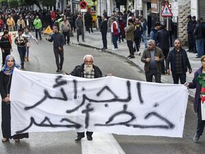 People march with a large banner reading in Arabic "Algeria is a red line" during a demonstration in the centre of the capital Algiers on November 30, 2019, in support of the upcoming presidential vote scheduled to take place in less than two weeks. (RYAD KRAMDI / AFP)