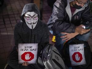 A participant wearing a Guy Fawkes mask holds a placard during a "Say no to tear gas" rally at Edinburgh place in Hong Kong on December 6, 2019. Philip FONG / AFP